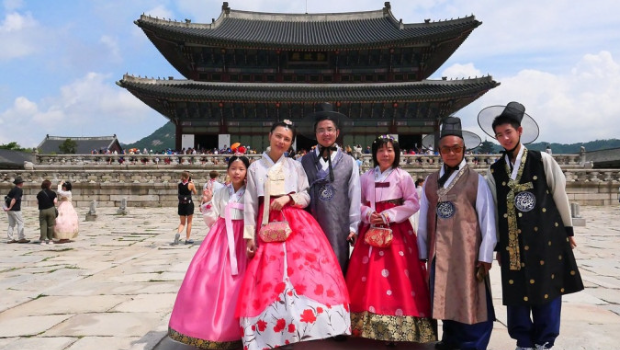 游客在韩国古建筑前穿韩服摄影留念。