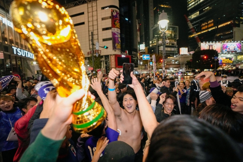 日本球迷在街頭高舉世界盃。Reuters