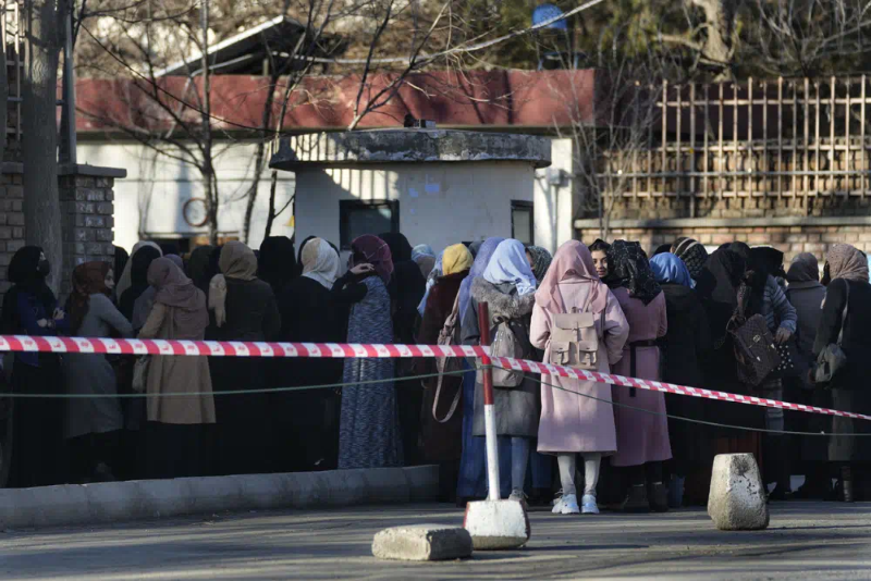 FILE - Afghan students queue at one of Kabul University's gates in Kabul, Afghanistan, on Feb. 26, 2022. Women are banned from private and public universities in Afghanistan with immediate effect and until further notice, a Taliban government spokesman said Tuesday, Dec. 20, the latest edict cracking down on their rights and freedoms. (AP Photo/Hussein Malla, File)