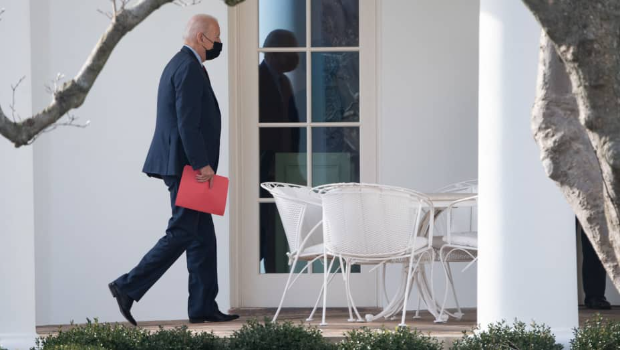 US President Joe Biden carries a red folder as he walks to the Oval Office at the White House in Washington, DC, on January 25, 2022, after returning from a surprise visit to nearby Barracks Row.