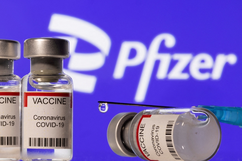 插图显示标有“VACCINE Coronavirus COVID-19”的小瓶和显示的辉瑞徽标前的注射器