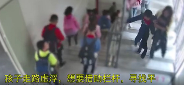 男童由老师搀扶走下楼梯时，之后摔倒。 网片截图