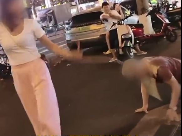 女子在海南街头拖男子爬行。