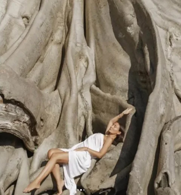 女子用床單包裹裸體，依偎在樹上。 IG
