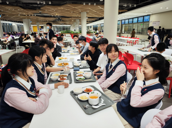 民心学校学生跟香港同学在饭堂共进晚餐，分享国内生活点滴。