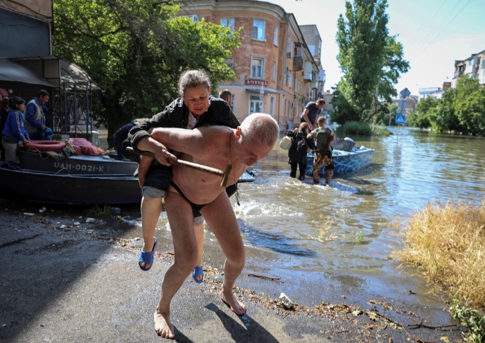 当地居民帮助从洪水泛滥的地区疏散一名妇女