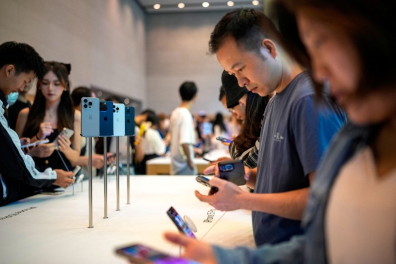 苹果 iPhone 15 在上海的一家苹果专卖店正式发售时，人们正在围观试用。 路透社