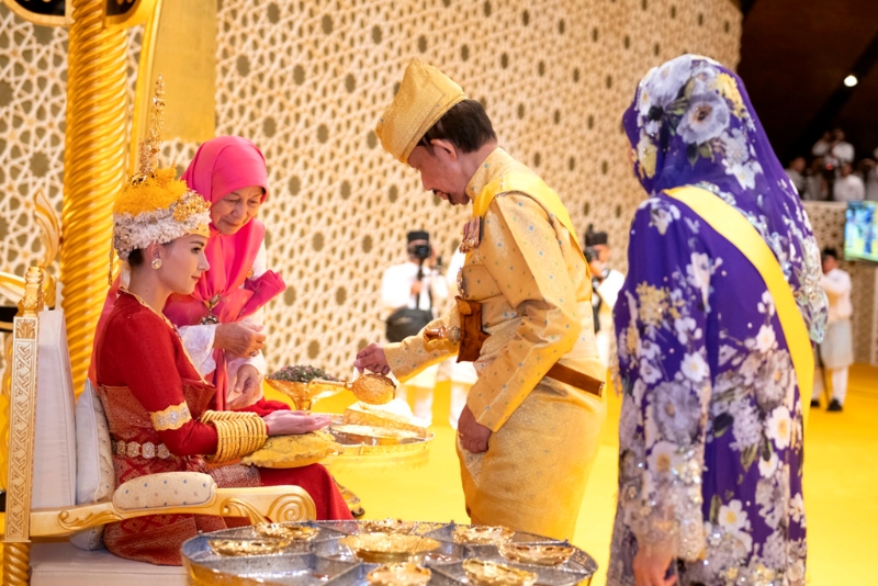 图为10日文莱苏丹哈山纳包奇亚（Sultan Hassanal Bolkiah）为马丁王子的新娘阿妮莎（Anisha Isa）（上图红衣坐下者）「扑粉」。 美联社