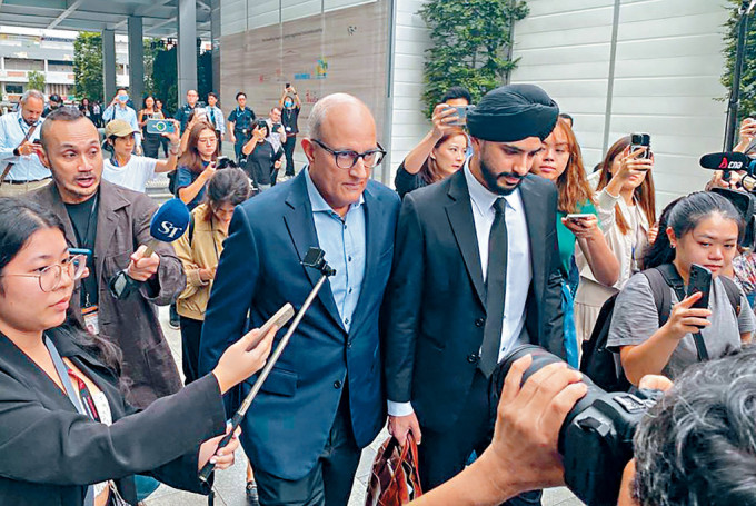 新加坡交通部部长易华仁（中左）周四出庭后离开国家法院。