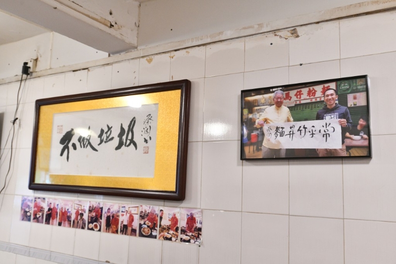 面店墙上挂起蔡澜和老板的合照，以及由蔡澜书写的不做垃圾四字。