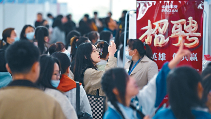 宁夏银川招聘会上，一女子用手机拍下岗位讯息。