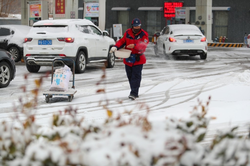 全国多地迎来降雪，2月1日，河南省商丘市的一名加油站工作人员在撒盐除雪。新华社