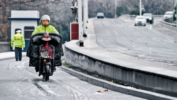 湖北武汉市民昨日在雨雪天气中出行。