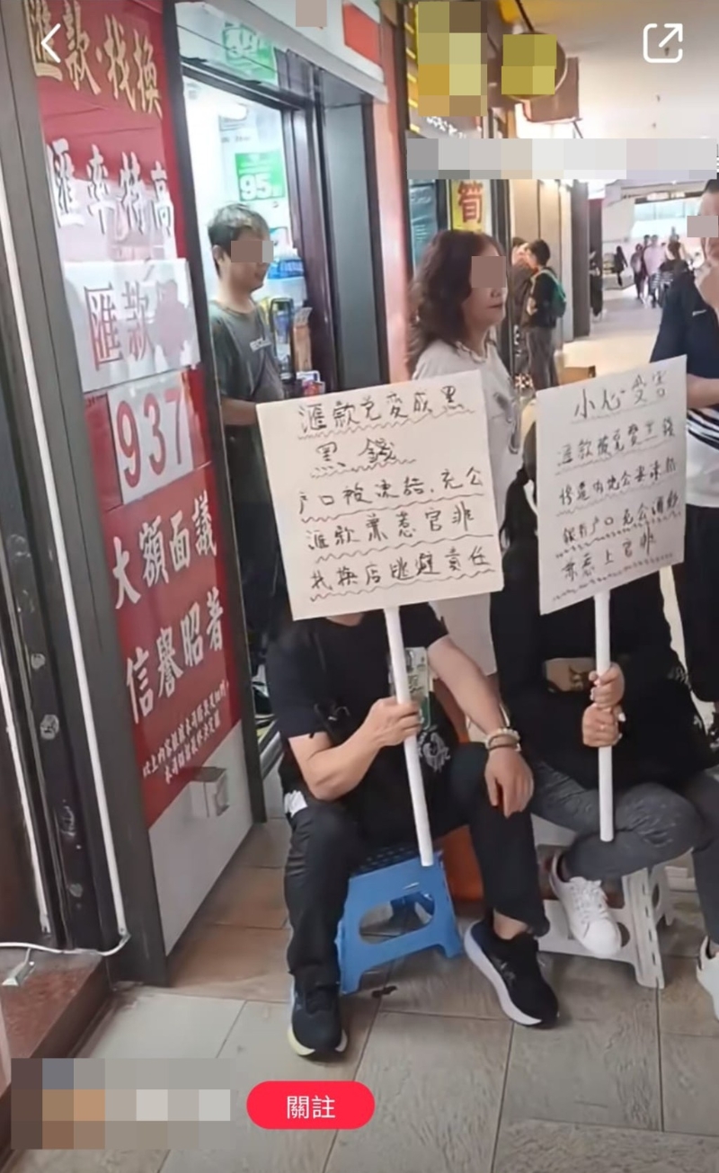 两人早前在沙田一找换店门外举起纸牌，抗议汇款人内地户口遭冻结。